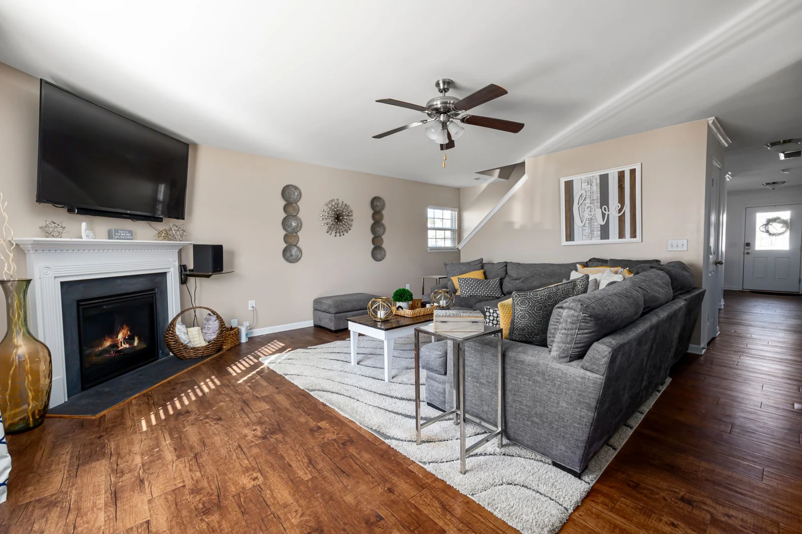 White mantel fireplace beside grey seating and a wooden floor
